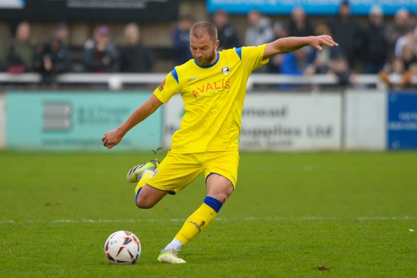 Weston-super-Mare footaller Luke Coulson striking the ball while wearing an all-yellow kit